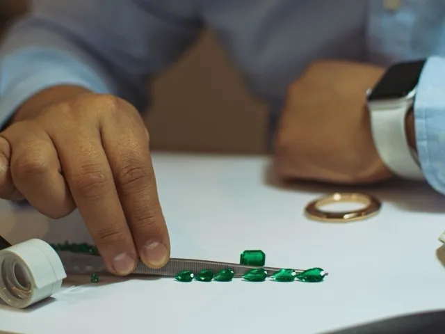 Ékszerbecsüs szakértő smaragdokat vizsgál és rendszerez az asztalon